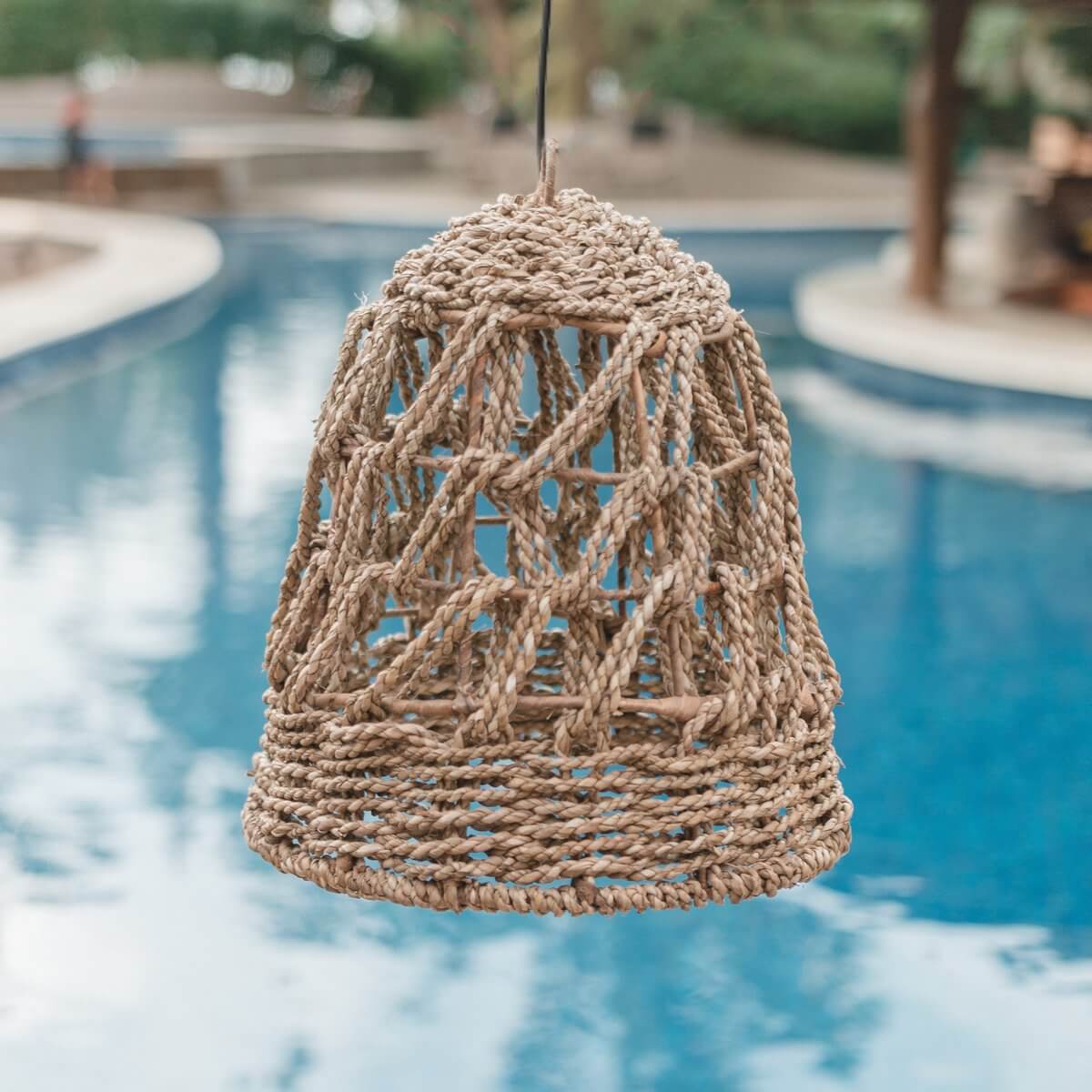 Ibiza lamp van zeegras met een tropische uitstraling, gehangen boven een zwembad, geschikt voor overdekte buitenruimtes.