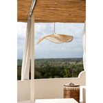 Loom Rotan Hanglamp in een buitenruimte, biedt subtiele verlichting en stijl boven een loungebank onder een overkapping.