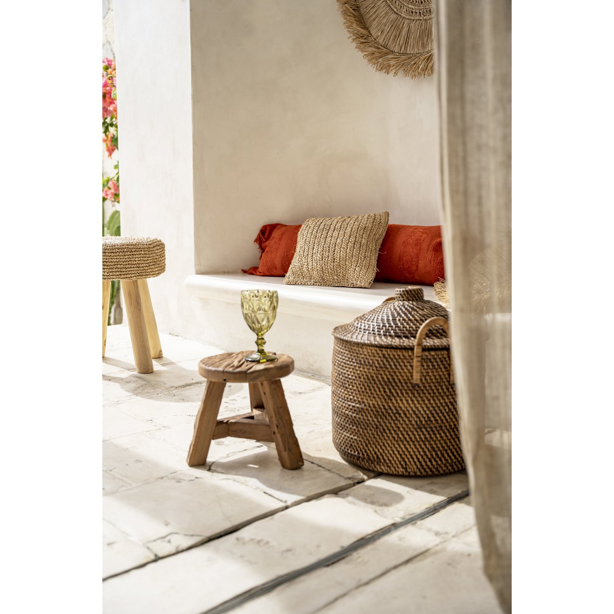 Kleine teakhouten kruk als bijzettafel in een bohemian interieur