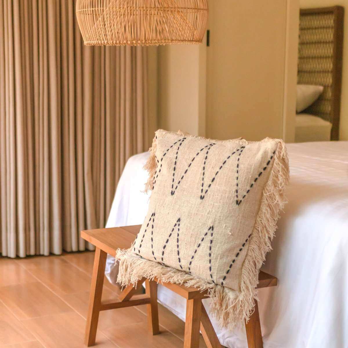 Crèmekleurige boho kussenhoes als sfeervolle decoratie op houten bankje in slaapkamer