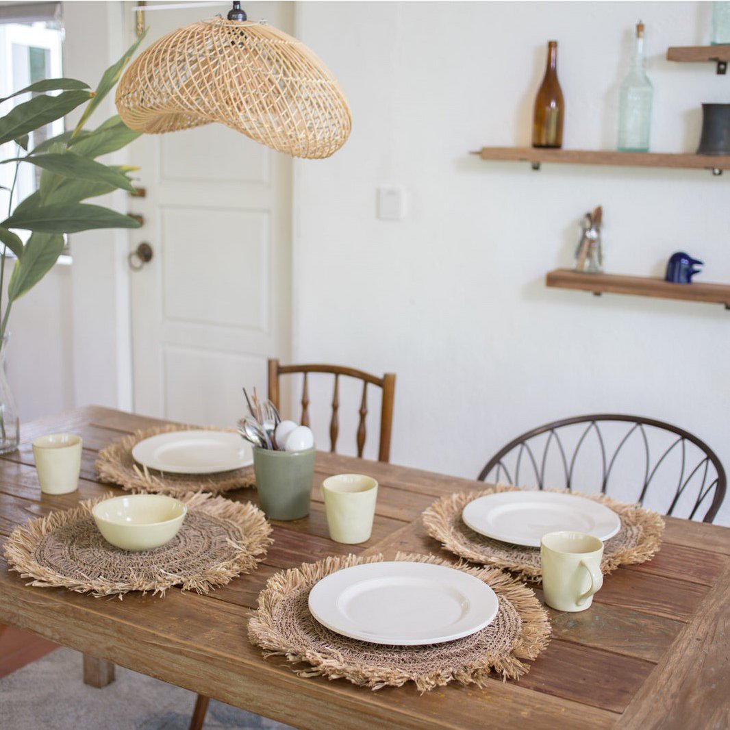 Boho hanglamp van rotan boven een houten eettafel voor een sfeervol interieur