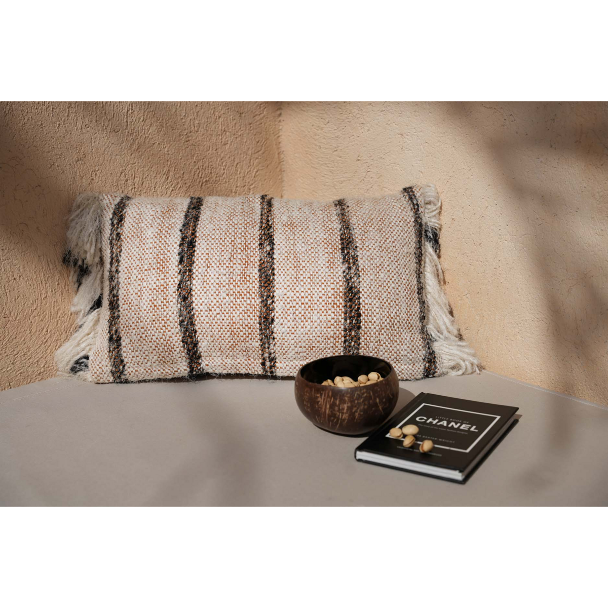 Ibiza Stripe kussenhoes in zachte boho sfeer, gestyled op tafel met kokosnootschaal en woonboek