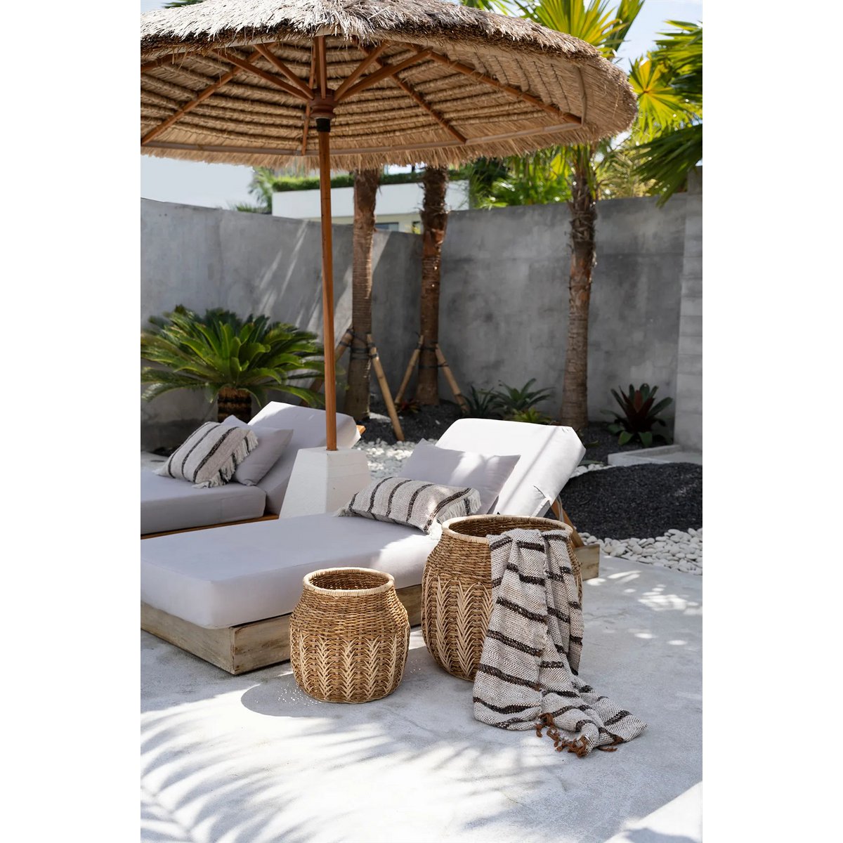 Zomerse Ibiza setting met boho kussenhoezen en parasol, gestyled met natuurlijke materialen en rotan