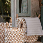 Set van Bumi Manden van bananenvezel op een veranda, boho gestyled met een zachte deken voor een warme en natuurlijke sfeer.