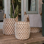 Drie Bumi Manden van bananenvezel bij een houten raamkozijn, met plant en plaid gestyled in boho sfeer voor binnen of buiten.