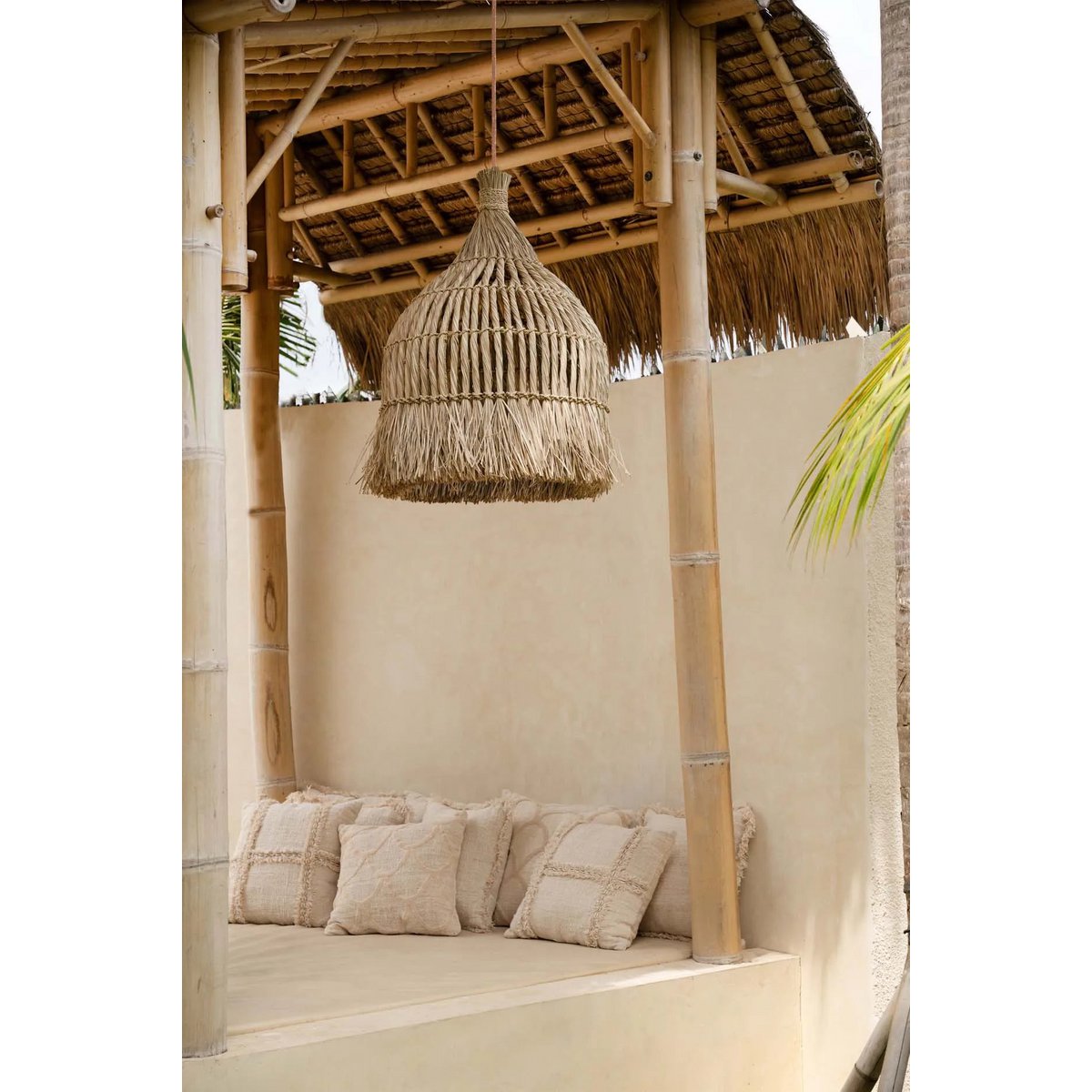 Maraluna lamp van mendonggras en waterhyacint, hangend boven een rustieke bamboe loungehoek.