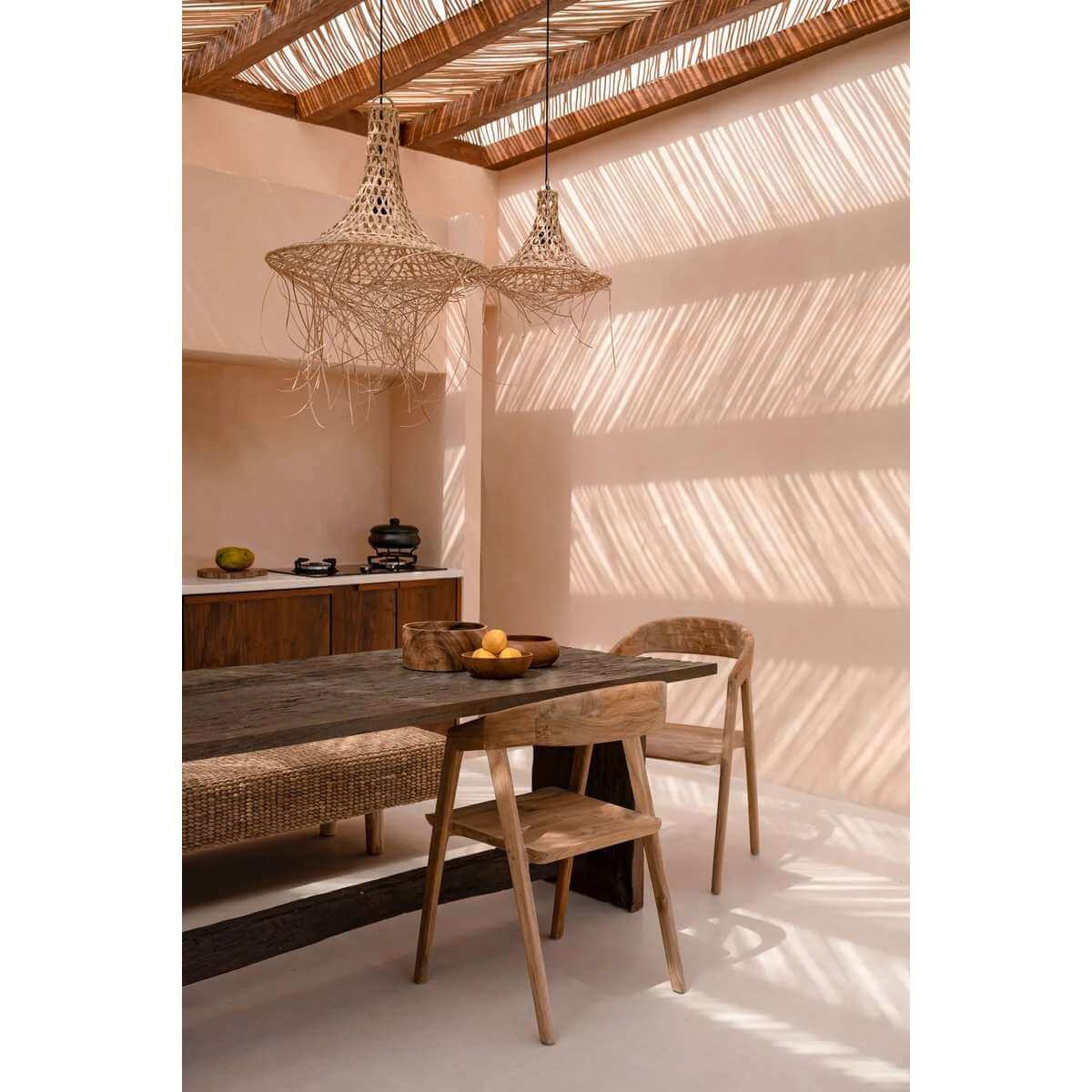 Twee rotan hanglampen Cala Mar op een overdekte veranda met prachtig schaduwspel – boho sfeerlicht boven houten buitentafel.