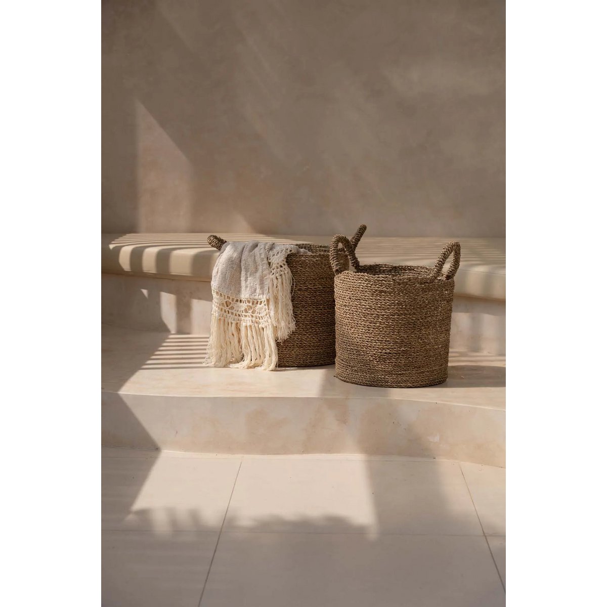 Beige Safiya Sprei met franjes gedrapeerd over opbergmand – Boho decoratie.