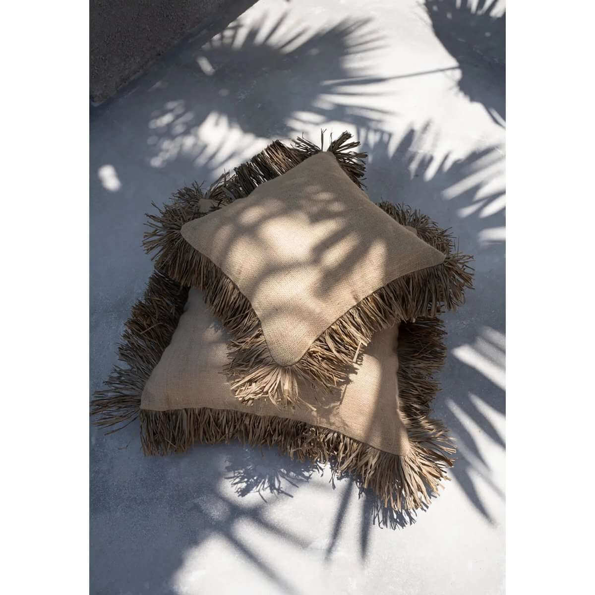 Twee boho kussenhoezen met raffia franjes, op elkaar gestapeld voor een natuurlijke look