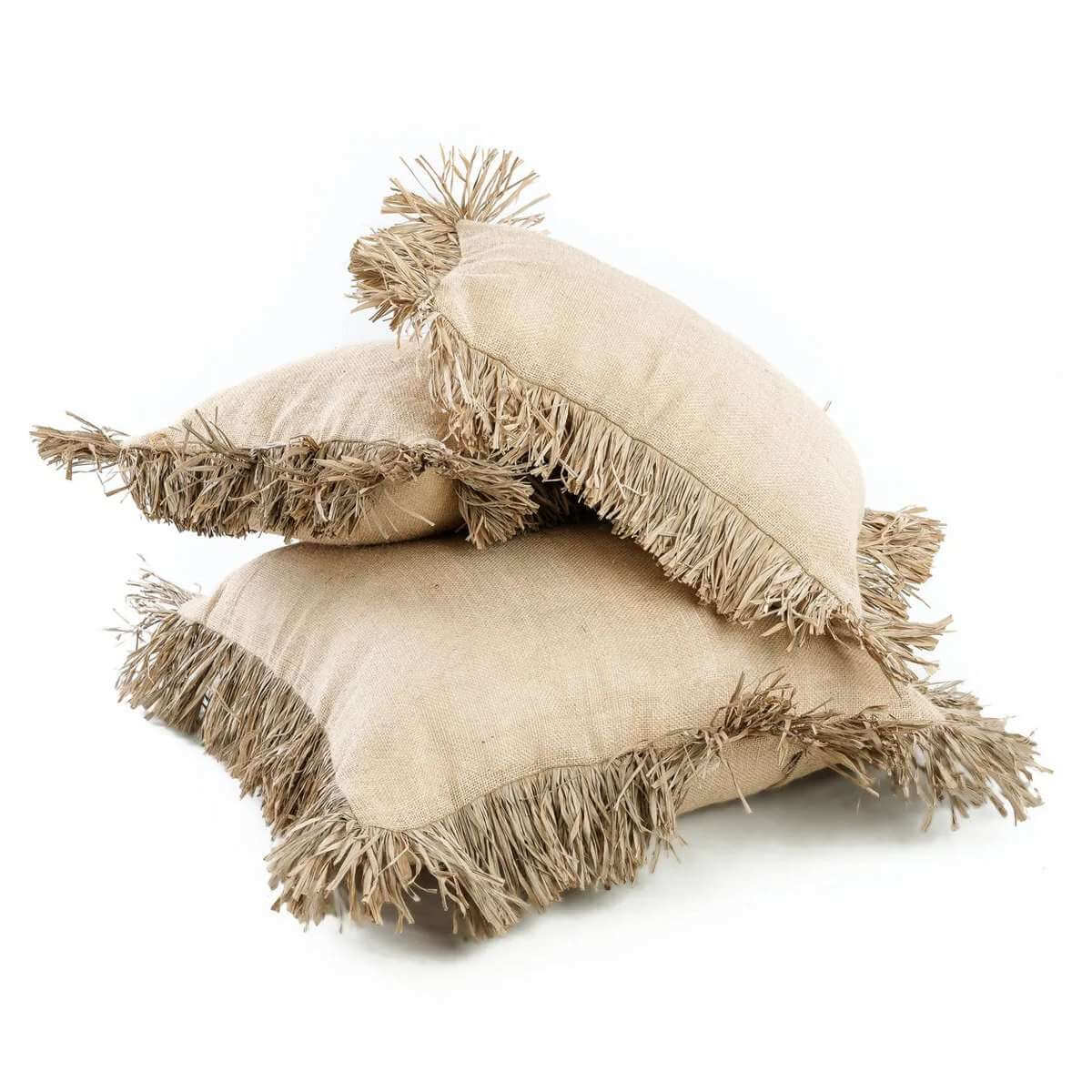 Drie boho kussenhoezen met raffia franjes, op elkaar gestapeld voor een natuurlijke look