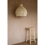 Solei Lume rotan hanglamp in boho interieur, een stijlvolle toevoeging boven een houten kruk