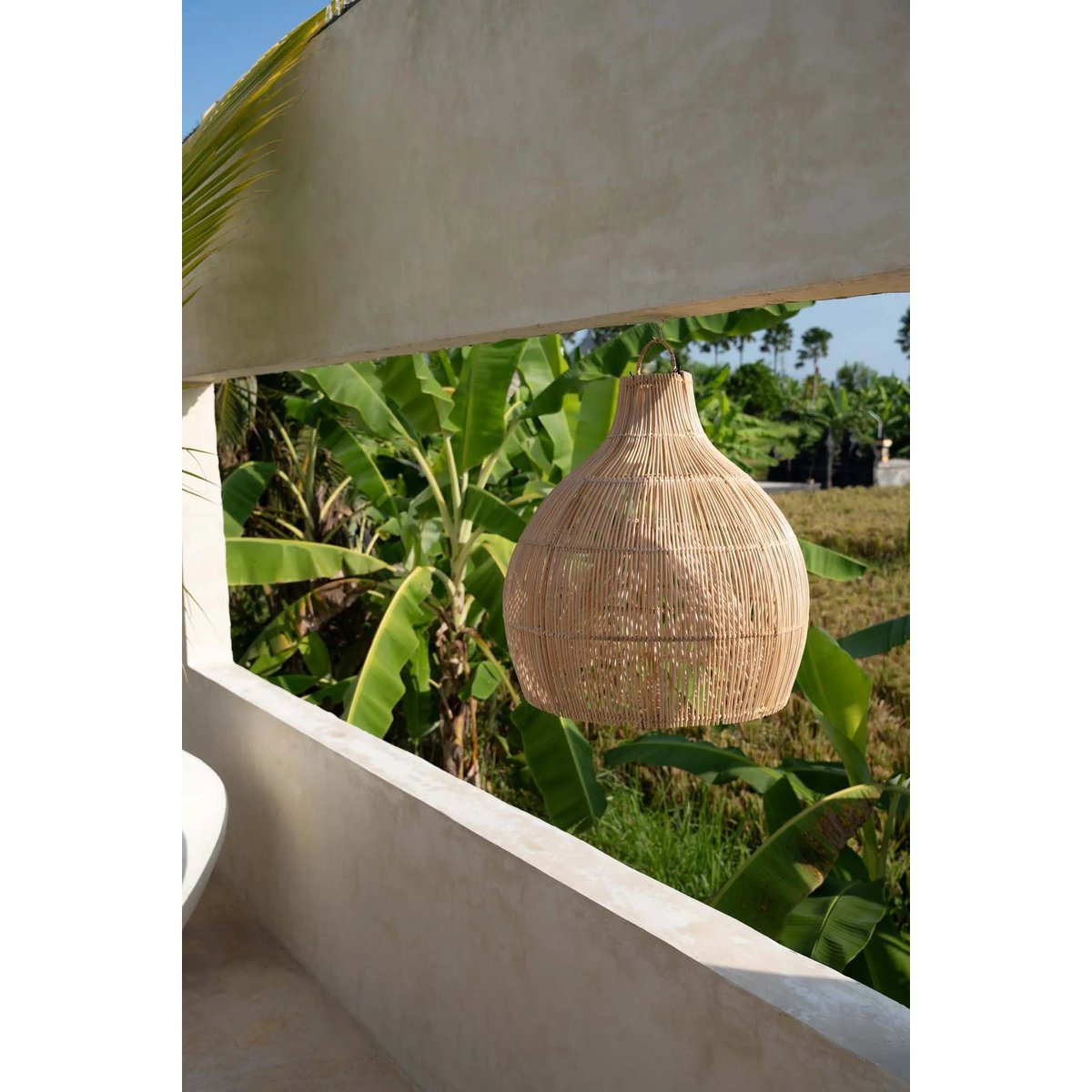 Solei Lume rotan hanglamp in tropische tuin, perfect voor een natuurlijke, boho uitstraling.