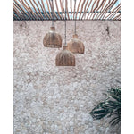 Solei Lume rotan hanglampen boven een stenen muur, perfect voor een boho of tropisch interieur.
