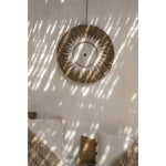 Boho wanddecoratie Soluna boven een bank met kussens in naturel tinten, sfeervol lichtspel